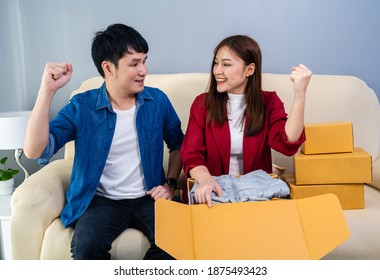 Happy Couple Open A Cardboard Parcel Box In The Living Room At Home, Purchase On Online Store