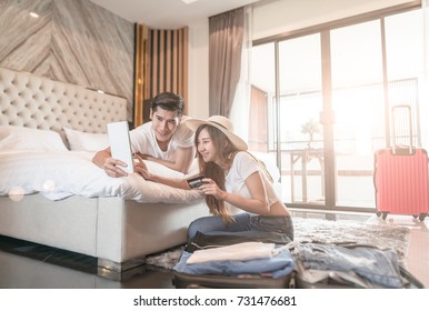 Happy couple packing suitcase on floor in room use tablet for search travel trip online use credit card - Powered by Shutterstock