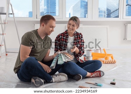 Happy couple with paint chips discussing interior details in apartment during repair