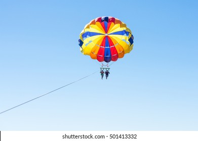 Happy couple Parasailing in Dominicana beach in summer. Couple under parachute hanging mid air. Having fun. Tropical Paradise. Positive human emotions, feelings, joy.