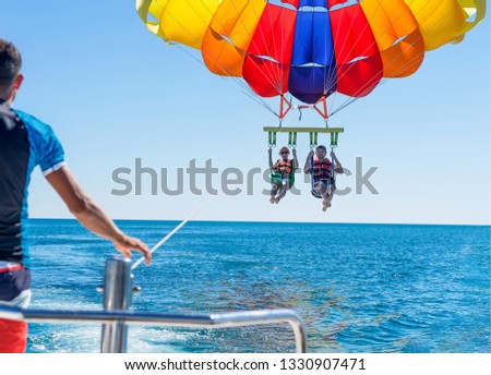 Happy couple Parasailing near Miami Beach in summer. Couple under parachute hanging mid air. Having fun. Tropical Paradise. Positive human emotions, feelings, family, travel, vacation.