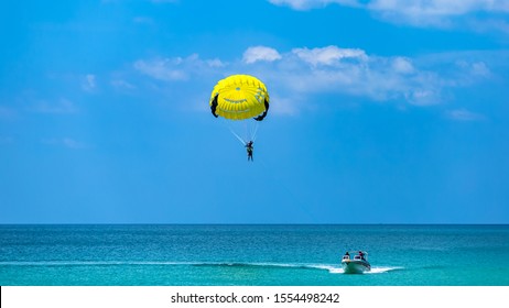 Happy couple Parasailing on Tropical Beach in summer, Tropical Paradis, With a parachute for parasailing a couple flies through the air with blue sky in the background.