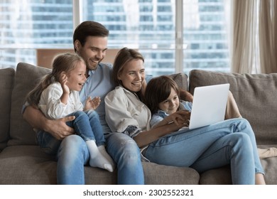 Happy couple of parents using online learning app on laptop, for educating little kids, resting on couch together, holding digital device, enjoying wireless technology, domestic internet connection - Powered by Shutterstock