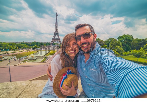 Happy couple in\
paris, France. Handsome tourist with hat with french flag taking\
picture selfie traveling in\
Europe