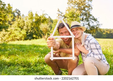 Happy Couple In The Park With House Folding Ruler As A Symbol Of Home Ownership And House Building Planning