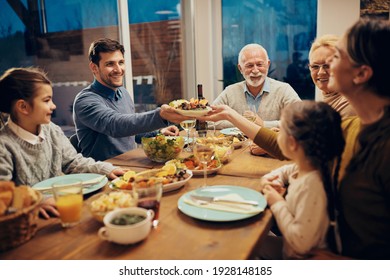 Happy couple passing food while having family lunch in dining room.  - Shutterstock ID 1928148185
