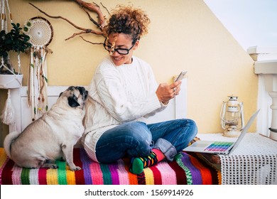Happy couple people and animals with cheerful beautiful caucasian woman and her lovely pug dog sit down at home while work with technology devices like phone and laptop