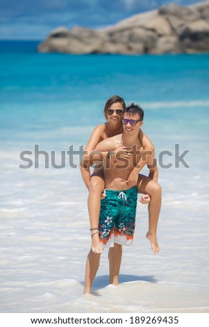 Happy couple piggybacking cheerful on beach during summer holidays vacation. couple in love having fun on tropical ocean beach.