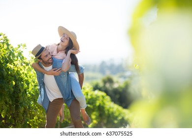 Happy couple piggybacking at vineyard during sunny day - Powered by Shutterstock