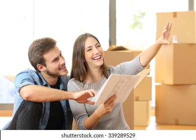 Happy couple planning decoration when moving home sitting on the floor
