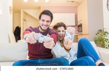Happy couple playing videogame at home on the sofa.