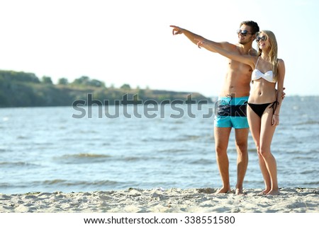 Happy couple pointing at the beach, outdoors