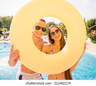 Happy Couple Are Posing With Rubber Ring In Swimming Pool.