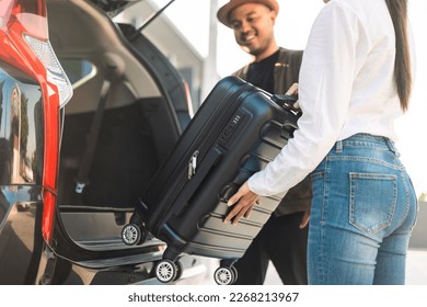 Happy couple puts his suitcase in the back of the car and prepares to leave for honeymoon trip. Husband and wife open the back of the car put luggage travel. Couple moving into new home at moving day - Shutterstock ID 2268213967