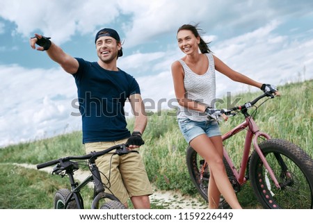 Happy couple racing on a bike along the sand and grass high in the mountains. 