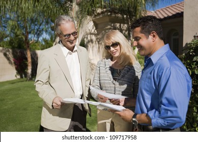 Happy Couple With Real Estate Agent Discussing Paperwork