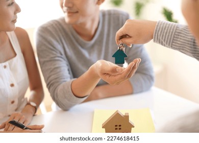 Happy couple receiving keys from new own property, finish meeting in real estate agency lead by realtor. Real estate purchase, success business contract deals with sale represent.