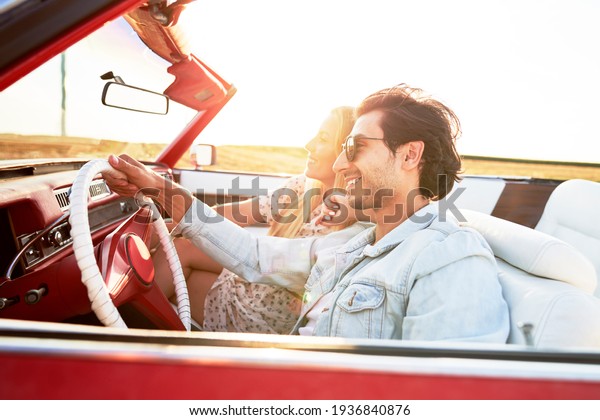 Happy couple in a red car at sunset                     \
         