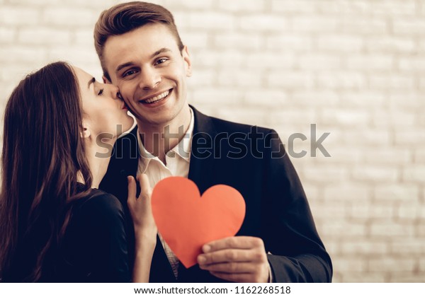 赤い心の折り紙を持つ幸せな夫婦 バレンタインデー 愛し合って 美しい祝日 スイートハートのお祝いのコンセプト 若くてハンサム 気持ちを示す 陽気な恋人 ロマンチックなキス の写真素材 今すぐ編集