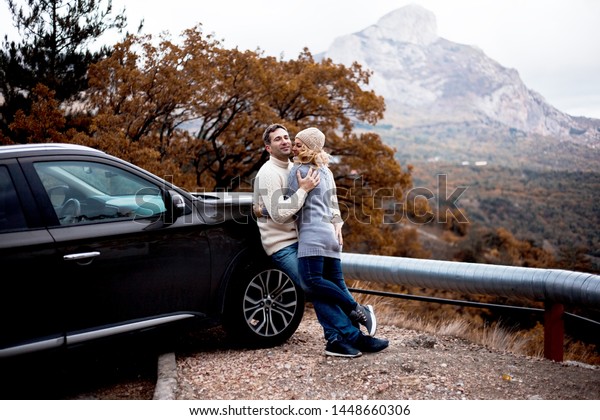 happy couple in relationship are hugging in\
countryside outdoor at fall day. man love his girlfriend. Two\
people kissing cling to the\
car