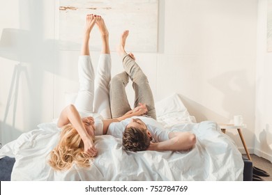 happy couple relaxing in bed and holding hands at morning