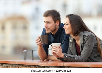 Happy couple relaxing drinking coffee in a balcony looking away on vacation - Powered by Shutterstock