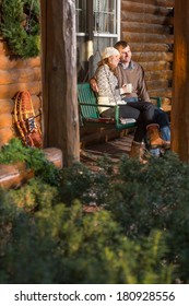 Happy Couple Relaxing On Log Cabin Porch