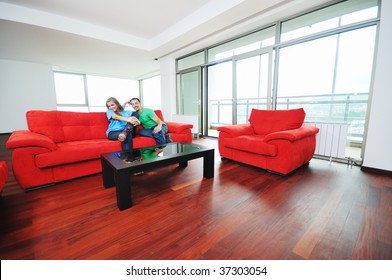 Happy Couple Relaxing On Red Sofa In Big Bright New Apartment