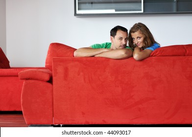 Happy Couple Relaxing On Red Sofa In Big Bright New Apartment