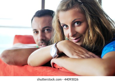 Happy Couple Relaxing On Red Sofa In Big Bright New Apartment