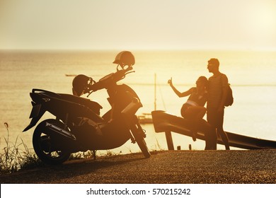 Happy couple relaxing at sunset time on sea backdrop near motorcycle on the border of road. Travel concept - Powered by Shutterstock