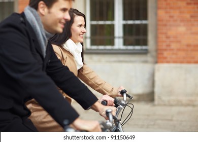 Happy Couple Riding Bikes Together In A City