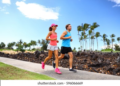 Happy Couple Of Runner Friends Running Training For Marathon Race Together In Summer Jogging On Street Sidewalk Neighborhood Park.