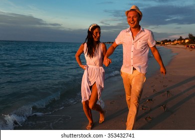 Happy Couple Running At The Night Beach Holding Hands