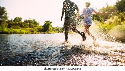 Happy Couple Running In Shallow Water. Summertime.