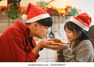 Happy couple with Santa hats sharing a romantic moment over a festive dish - Powered by Shutterstock