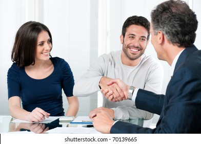 Happy Couple Seal A Deal With Their Personal Financial Advisor At Home