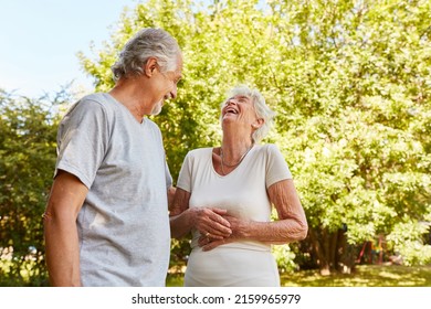 Happy Couple Of Seniors In Nature Talking And Laughing Out Loud With Their Hands On Their Stomachs