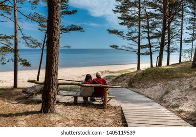 Happy couple of seniors are resting and looking at a distance near a sandy beach of the Baltic Sea - Powered by Shutterstock