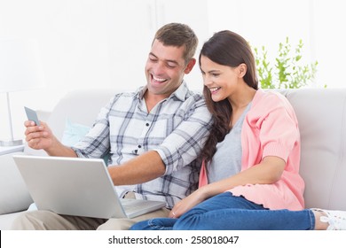 Happy Couple Shopping Online Through Laptop Using Credit Card At Home