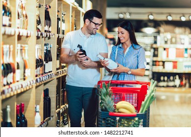 Happy couple shopping in supermarket buying wines