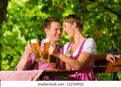 Happy Couple Sitting In Beer Garden In Summer And Enjoy A Glass Of Beer And The Sun