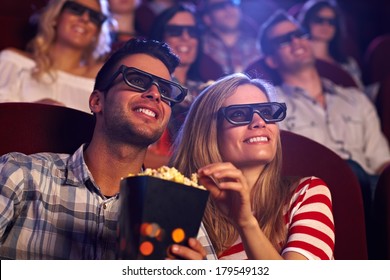 Happy Couple Sitting In Movie Theater, Watching 3D Movie, Eating Popcorn, Smiling.