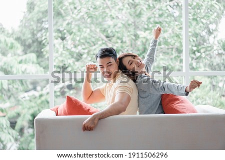 Happy couple sitting on the sofa and being a man teases his girlfriend with love in the living room and relax. Concept of romantic on valentine day. Proposal and marriage