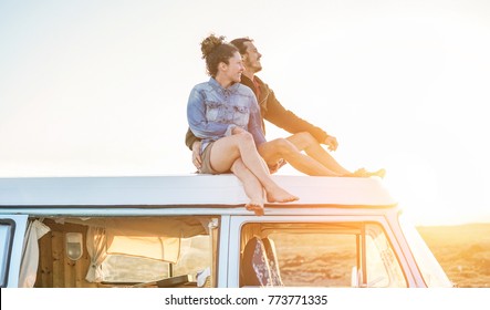 Happy Couple Sitting On Top Of Minivan Roof At Sunset - Young People Having Fun On Spring Vacation Traveling Around The World - Travel,love And Holiday Concept - Focus On Faces