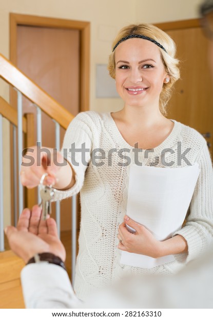 Happy couple sitting at the table with keys and\
documents at the home 
