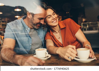 Happy couple sitting together at a coffee shop and relaxing. Couple in love meeting at a cafe with coffee on table. - Powered by Shutterstock