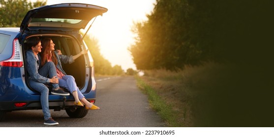 Happy couple sitting in trunk of their new car outdoors at sunset - Powered by Shutterstock