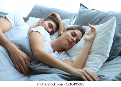 Happy couple sleeping in a comfortable bed at home.