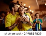 Happy couple of soccer fans celebrating victory of their favorite team in a bar.